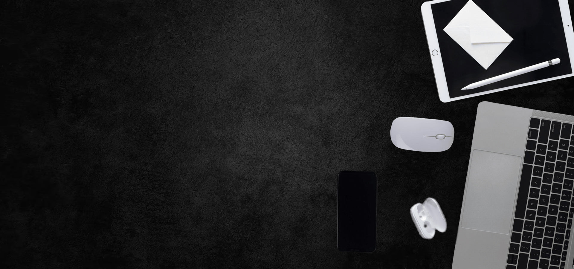 Laptop, tablet, smartphone, and mouse on a dark surface